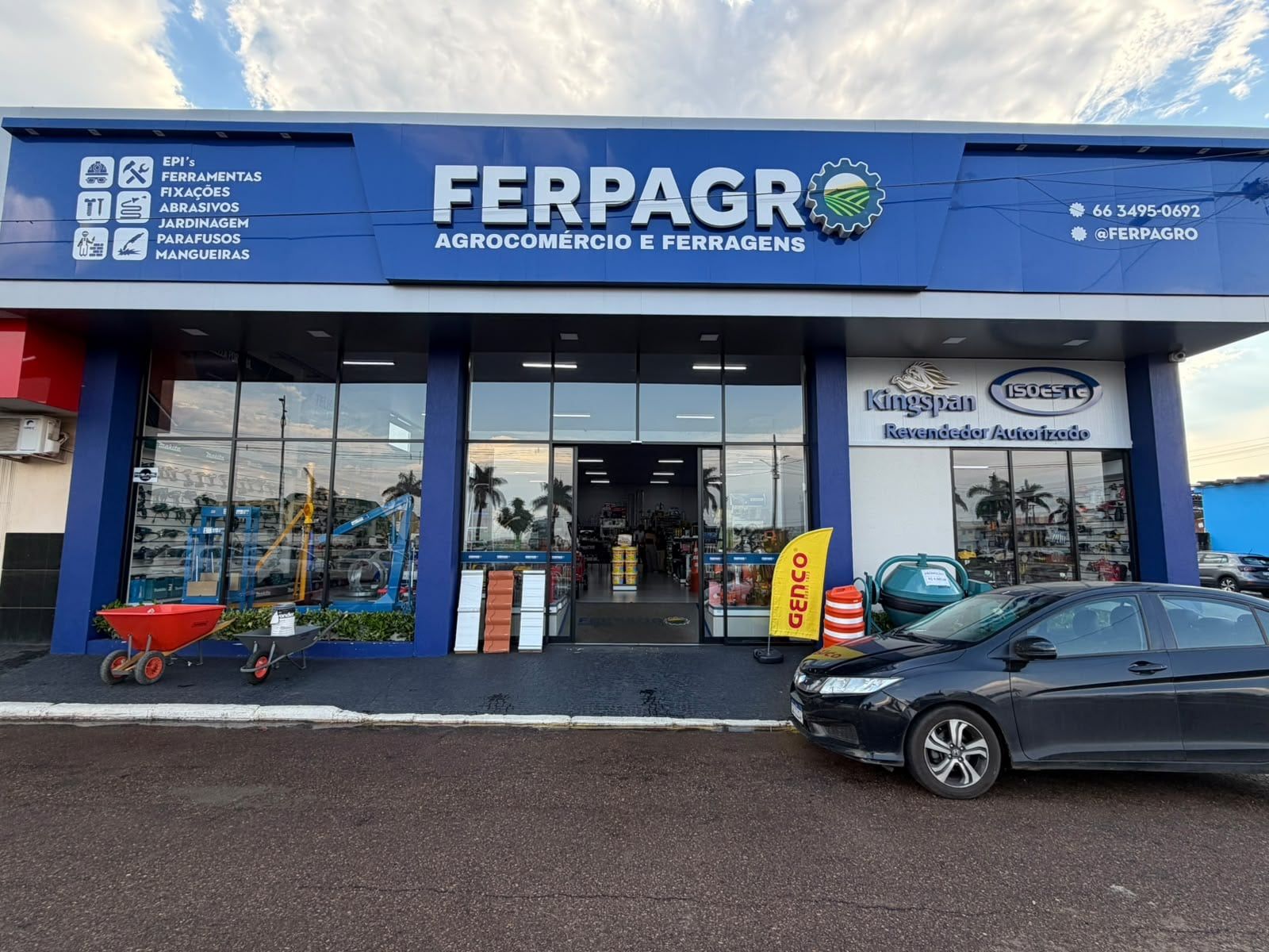 Fachada azul da Ferpagro na Rua Aripuanã, com o letreiro “Ferpagro — Agrocomércio e Ferragens”, a lista de linhas da loja e a placa de revendedor autorizado Kingspan Isoeste