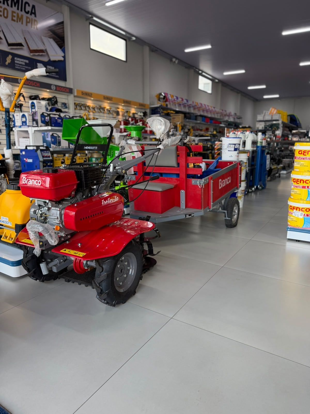 Motocultivador Branco vermelho com carreta no salão da loja